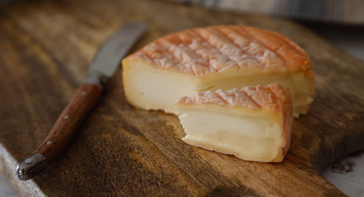 Wheel of Epoisses cut into wedges on wooden cutting board