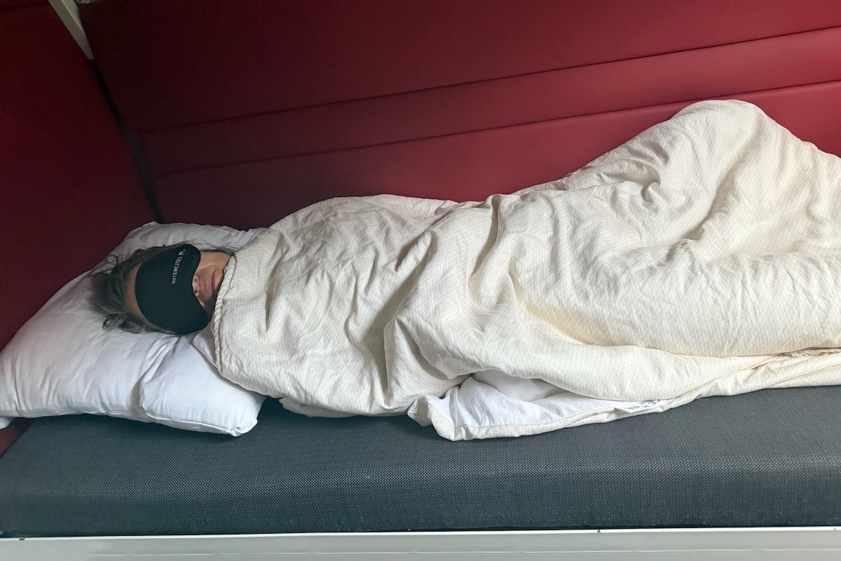 Woman sleeping in bunk bed in sleeper train car.