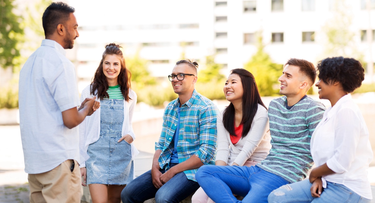 Group of smiling friends sitting on park bench