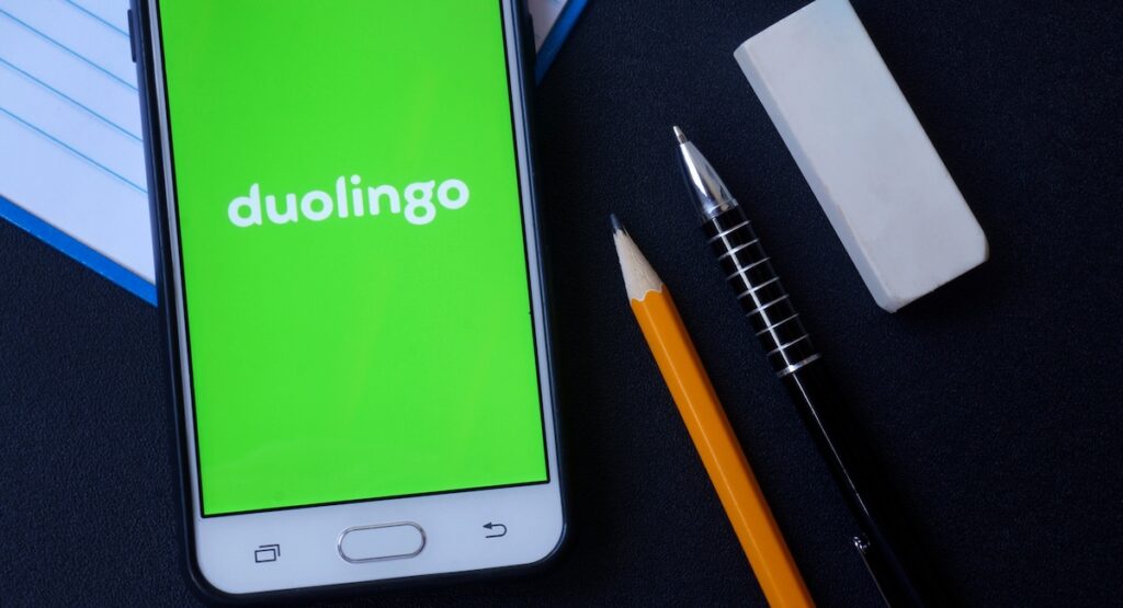 Phone with Duolingo app running beside pen and pencil