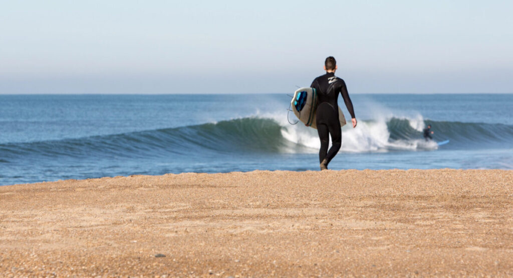 Young man with surf board walking on the beach.