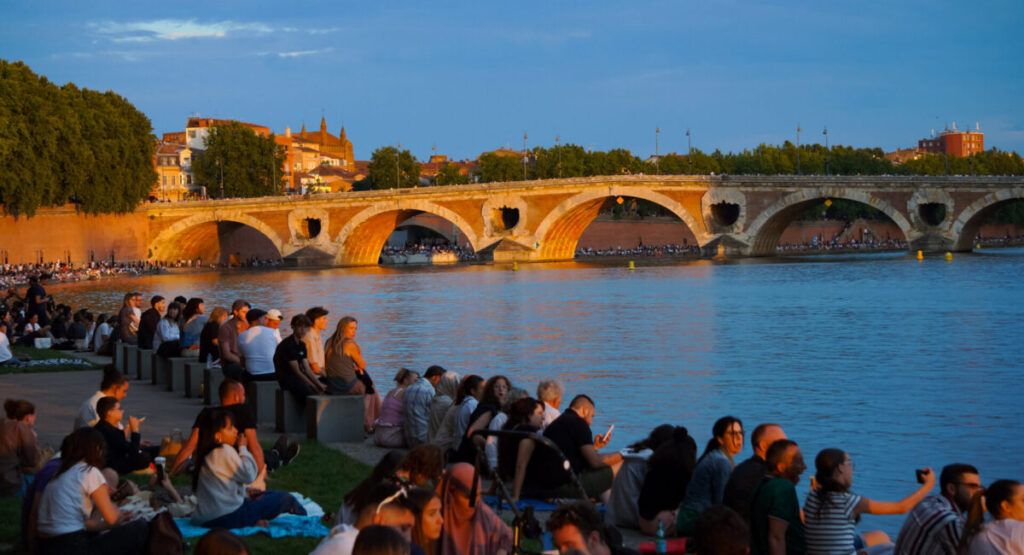 People sitting on the Quai de la Daurade at sunset.