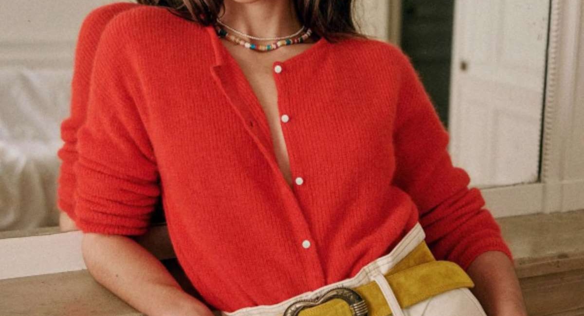 Woman wearing red cardigan standing in front of mirror