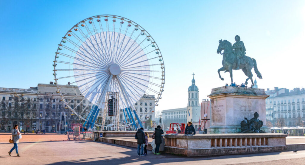 Place Bellecour in Lyon, with a statue and a ferris wheel.
