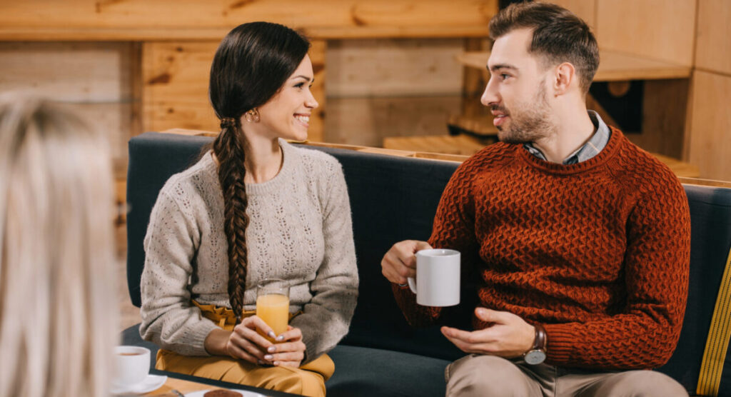 Smiling friends chatting in cafe.