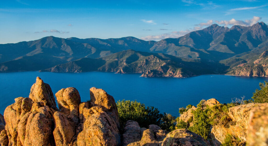 Panoramic view of the Gulf of Porto with rocks in the foreground.