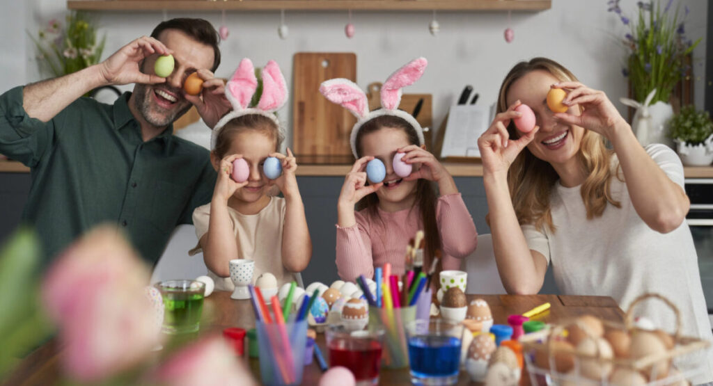 Portrait of playful family covering eyes with easter eggs.