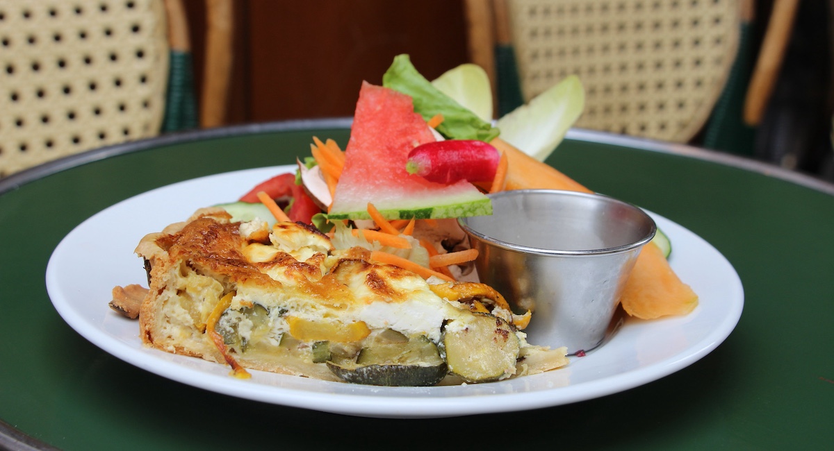 Quiche and salad on green bistro table.