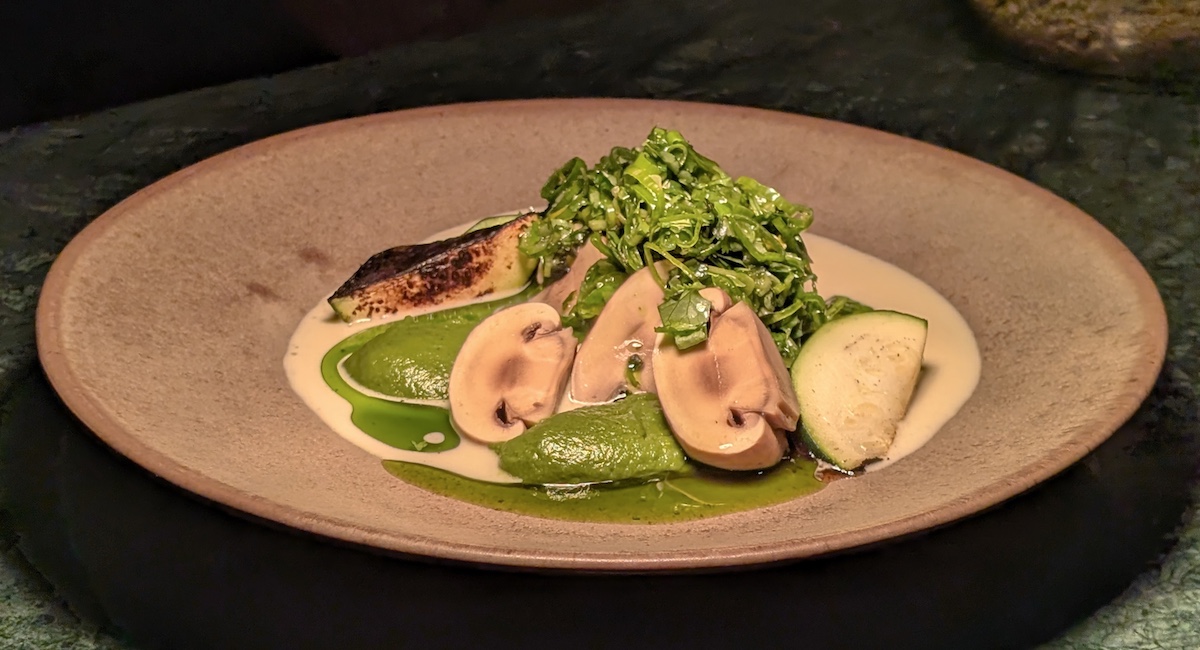 Zucchini dish with mushrooms on taupe plate.