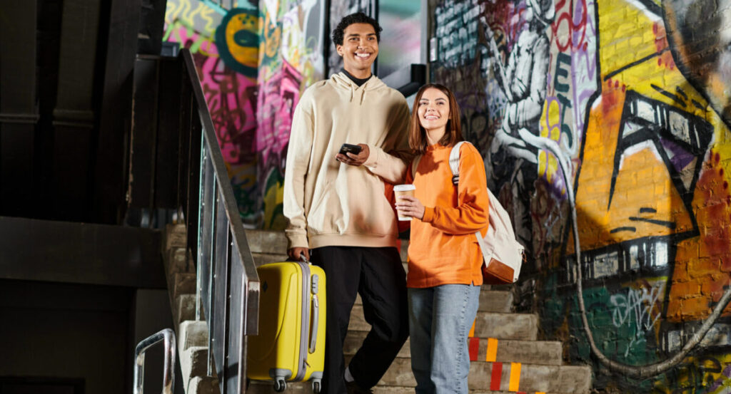 Diverse couple standing on stairs with graffiti on wall.