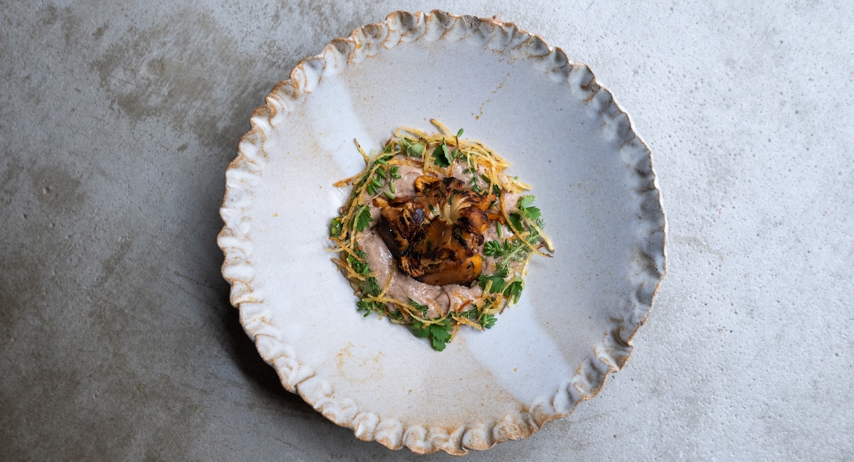Fine dining dish plated on handmade plate with crimped edges.
