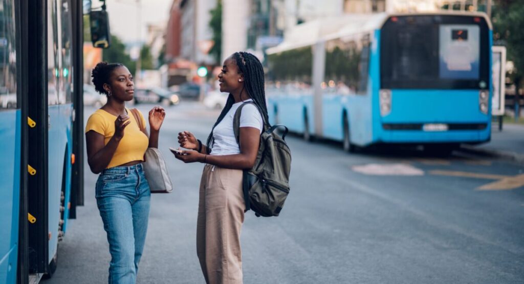 Two young women having a discussion at a bus stop.