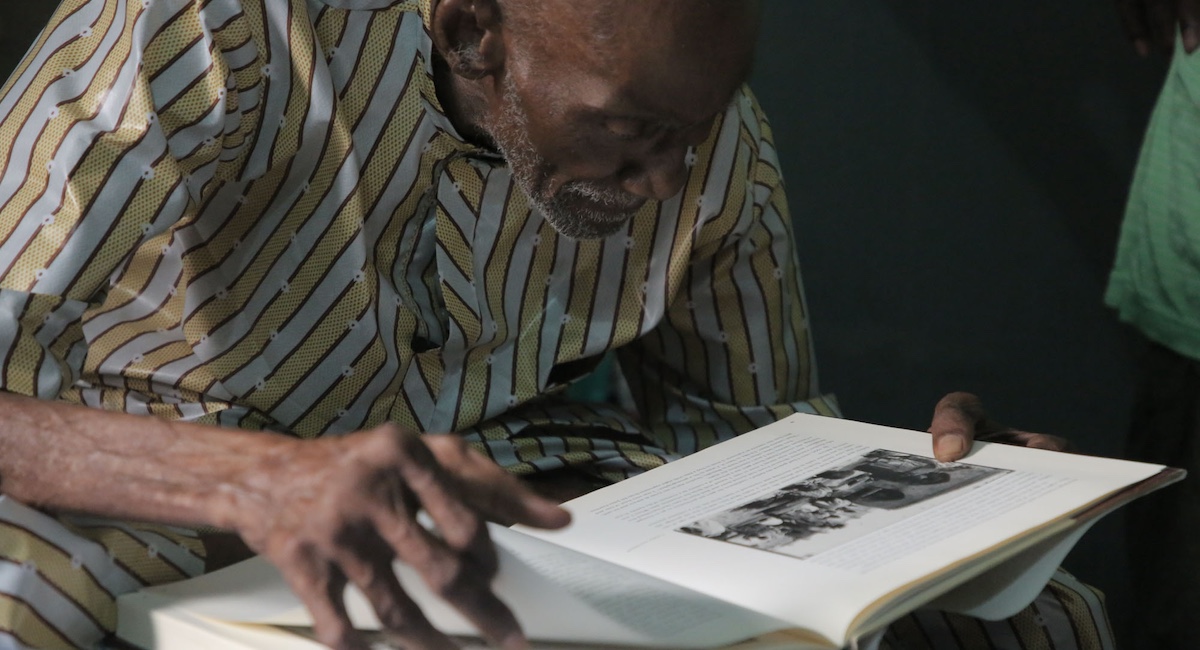 Man bent over book of photographs.