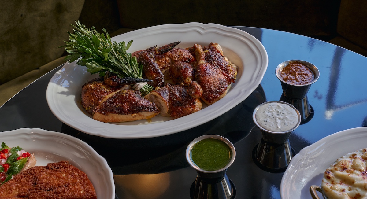 Rotisserie chicken on china tray with sauces.