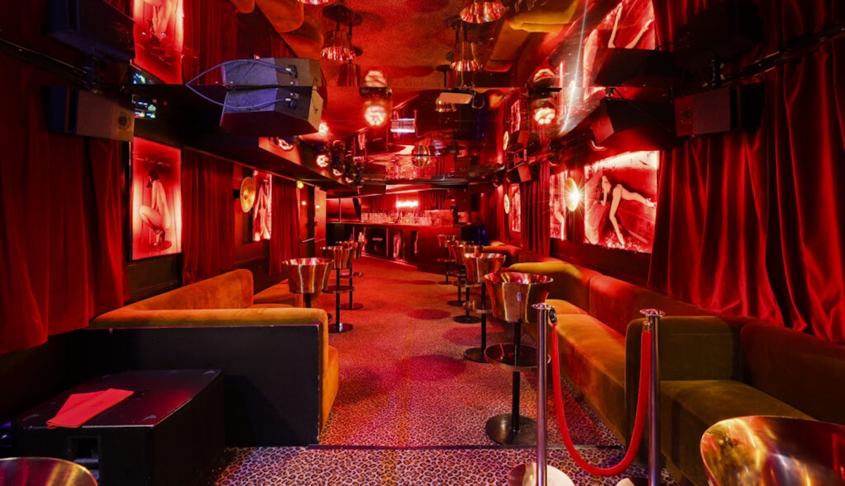 Bar interior with red lighting and velvet rope.