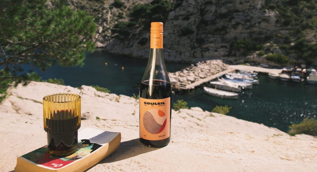 Bottle of red wine against ocean backdrop.