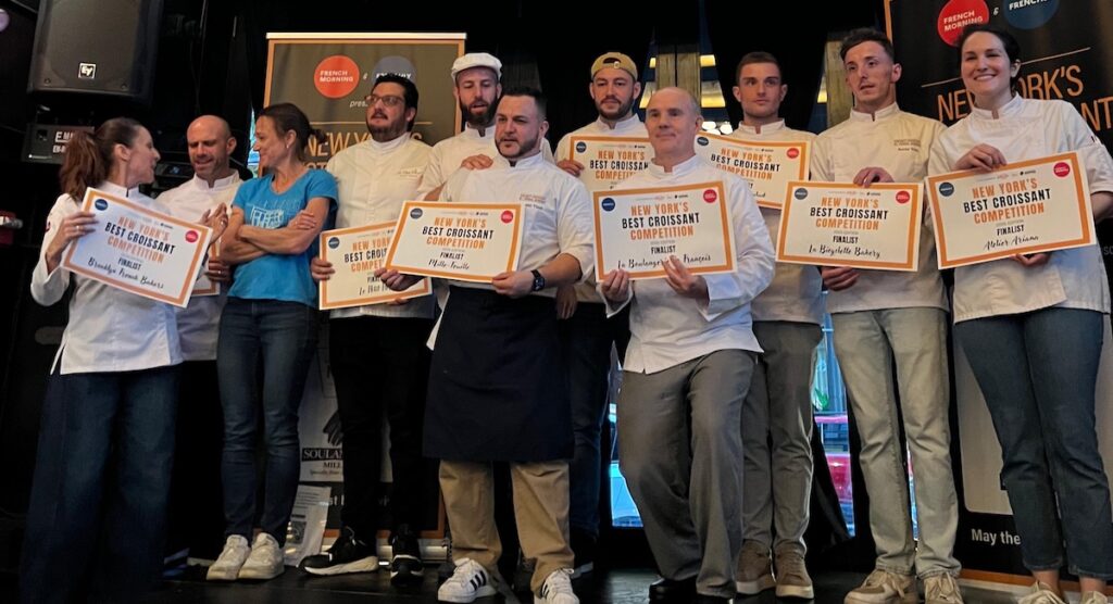 Winners of the Best Croissant Competition standing on a stage in chef's whites.