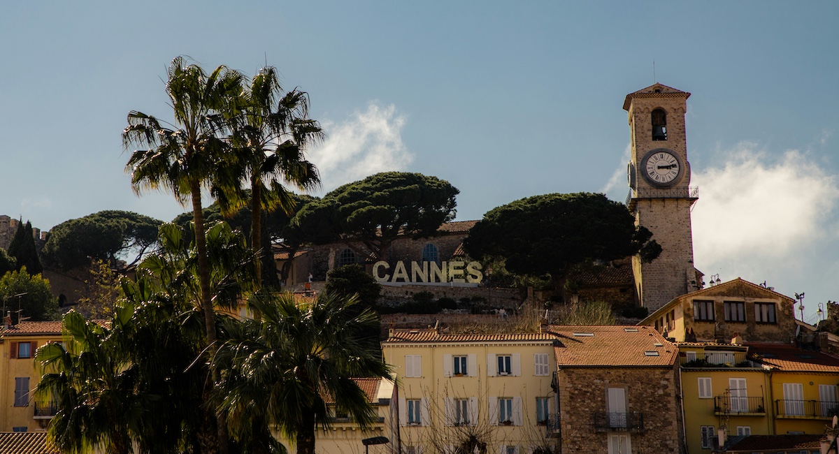 'Cannes' sign in South of France surrounded by buildings and palm trees.