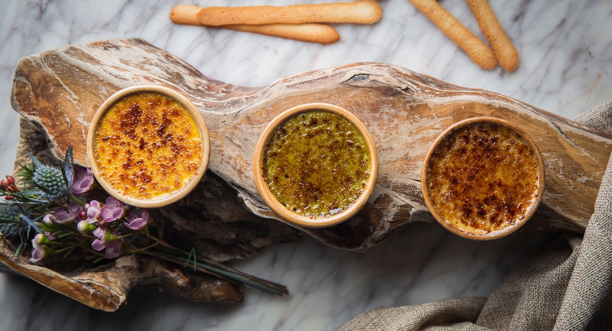 Trio of crème brûlées on wooden planche.