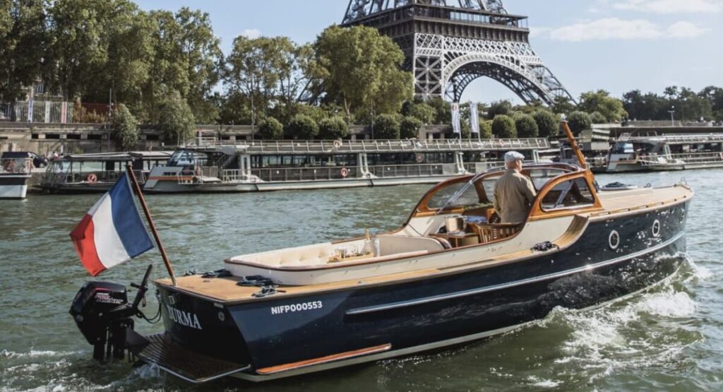 Boat flying French flag passes the Eiffel Tower in background.
