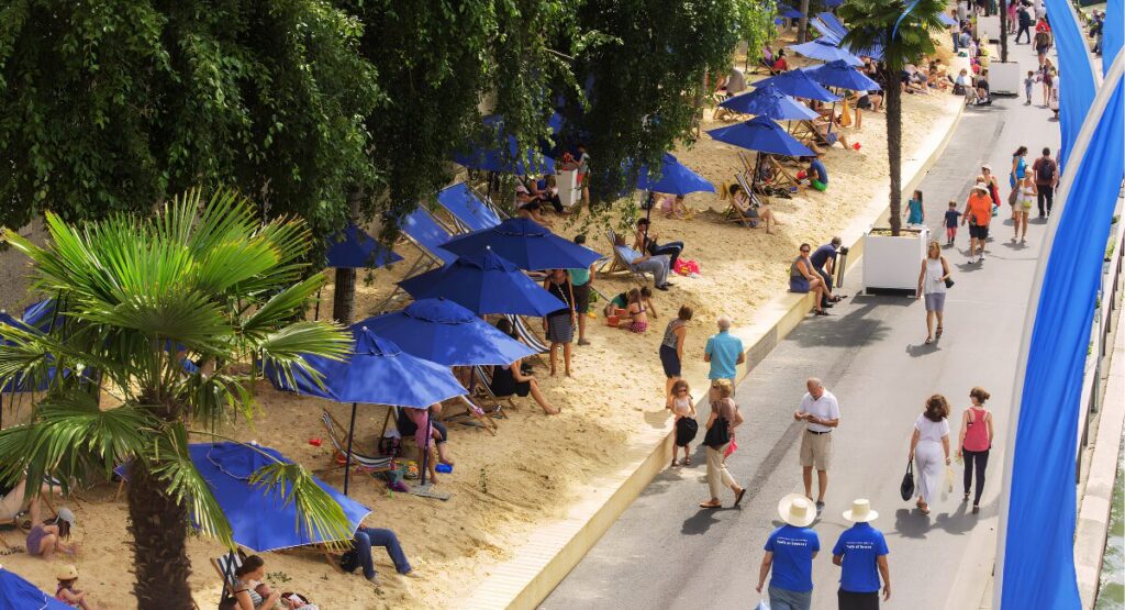 People lounging under beach umbrellas on the temporary beaches created for Paris Plages.