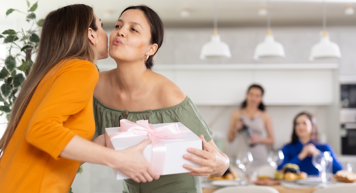 Smiling Asian woman hosting guests at home, greeting them as they arrive for a dinner party.