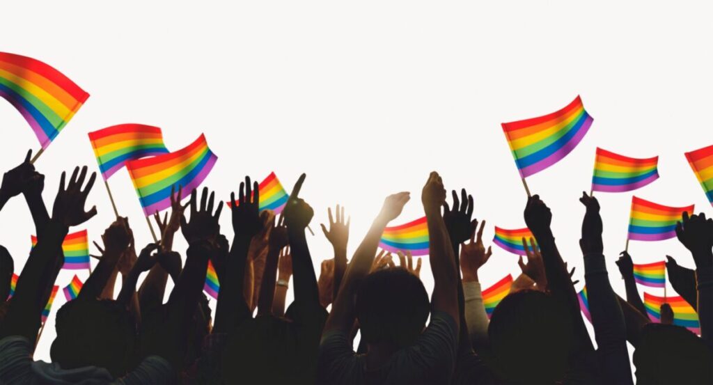 Hands in the air with the LGBTQ+ flag.