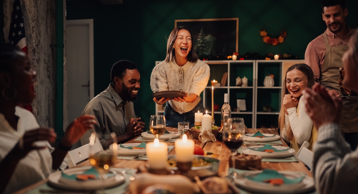Group of friends laughing at a dinner party.