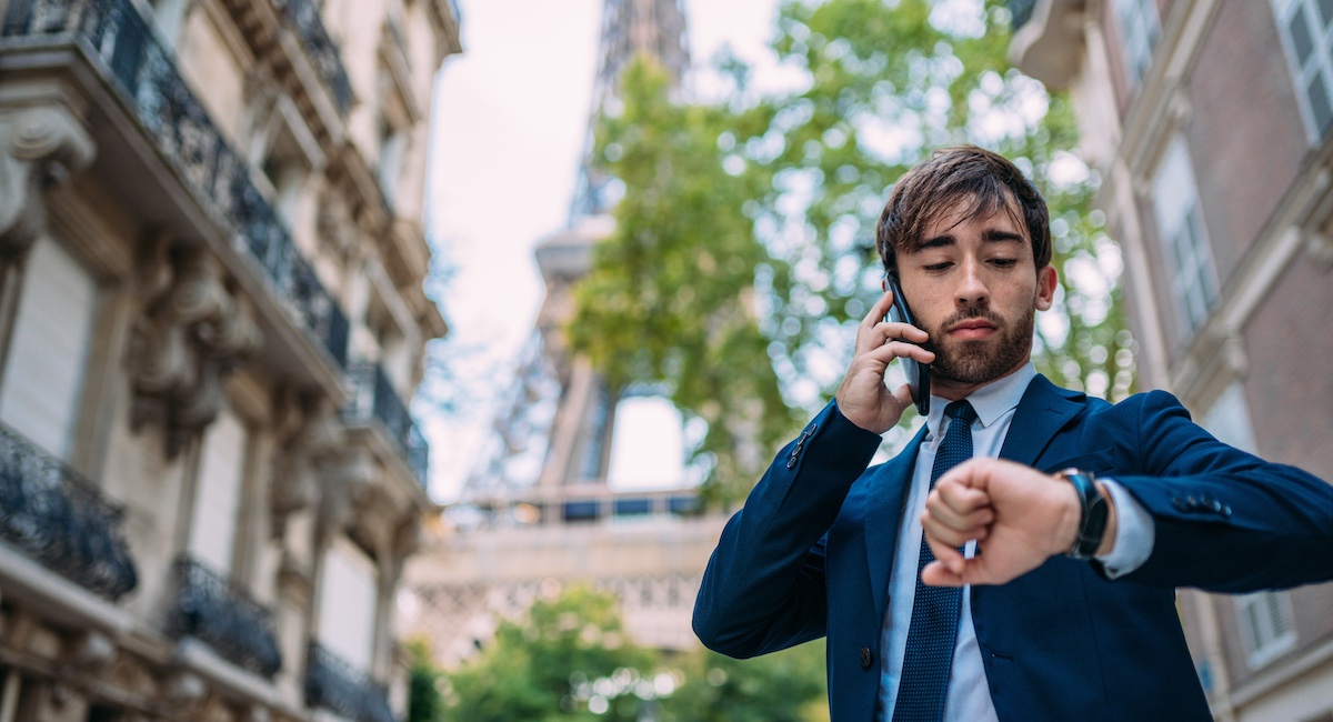 Man in a suit on the phone in front of Eiffel Tower.