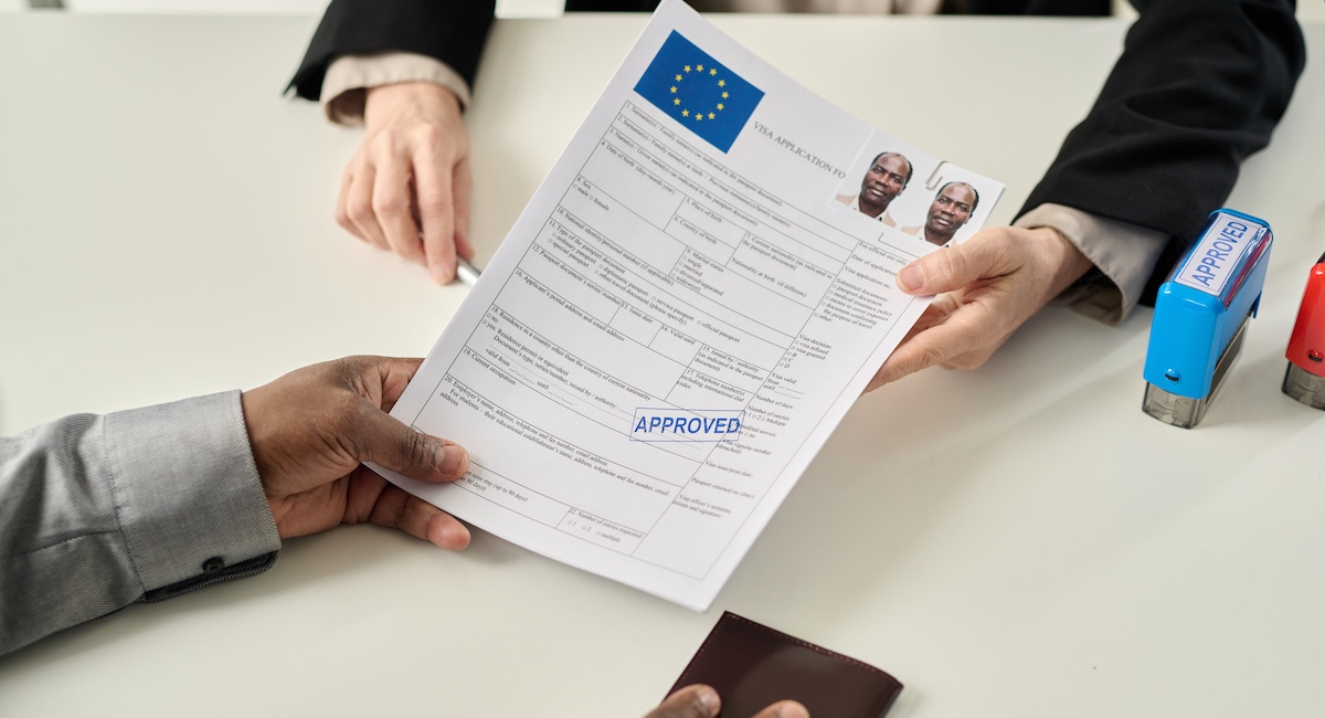Top view closeup of black man holding approved visa application form in immigration office.