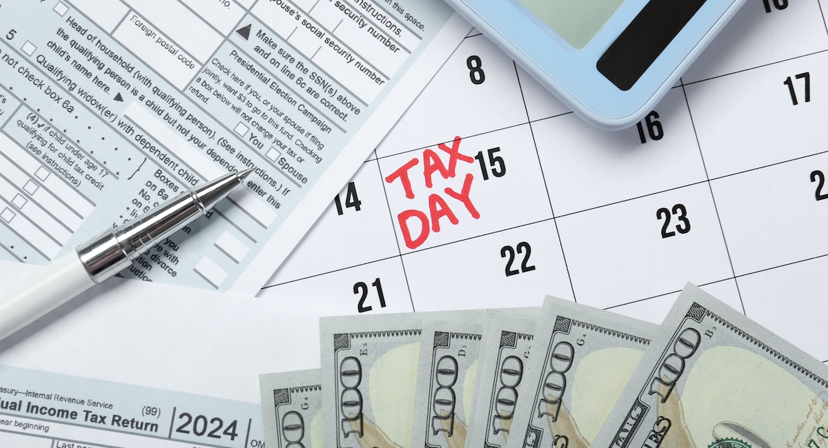 Calendar with date reminder about tax day, documents, money, pen and calculator.