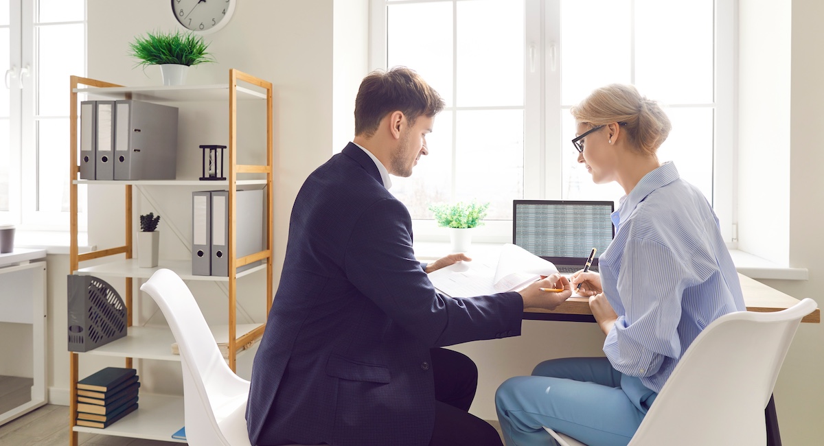 Tax expert advising woman while looking through paperwork.