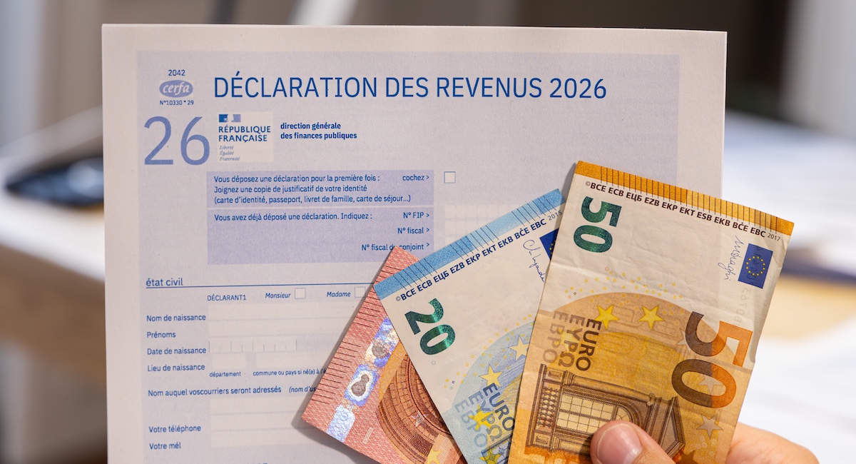 Tax return for France behind handful of euro bills.