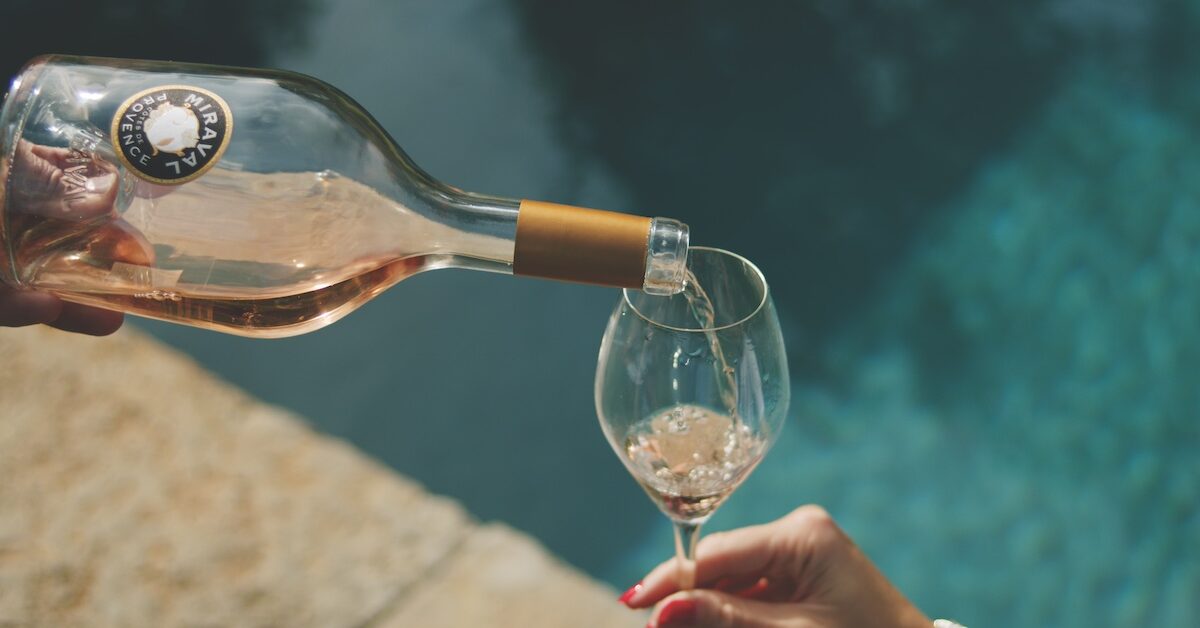 Bottle of rosé wine being poured by pool