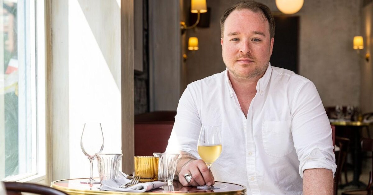 Man drinking white wine at bistro table
