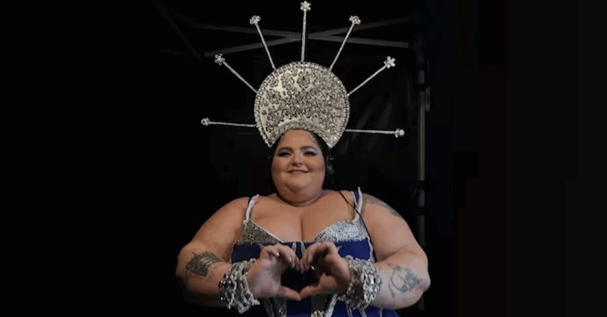 Woman making a heart with her hands, wearing elaborate headdress