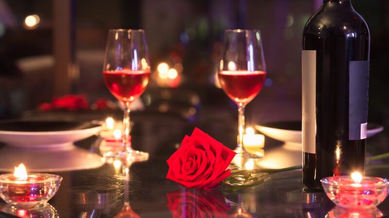 Candlelit dinner set with roses and two glasses of wine.