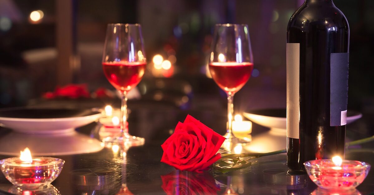 Candlelit dinner set with roses and two glasses of wine.