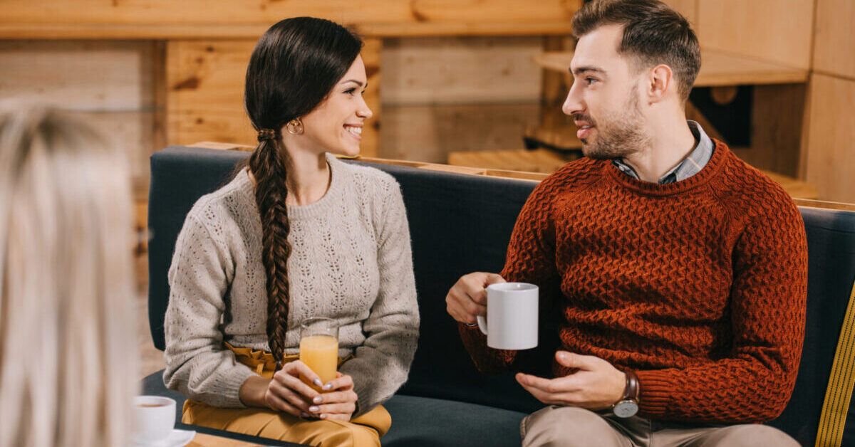 Smiling friends chatting in cafe.