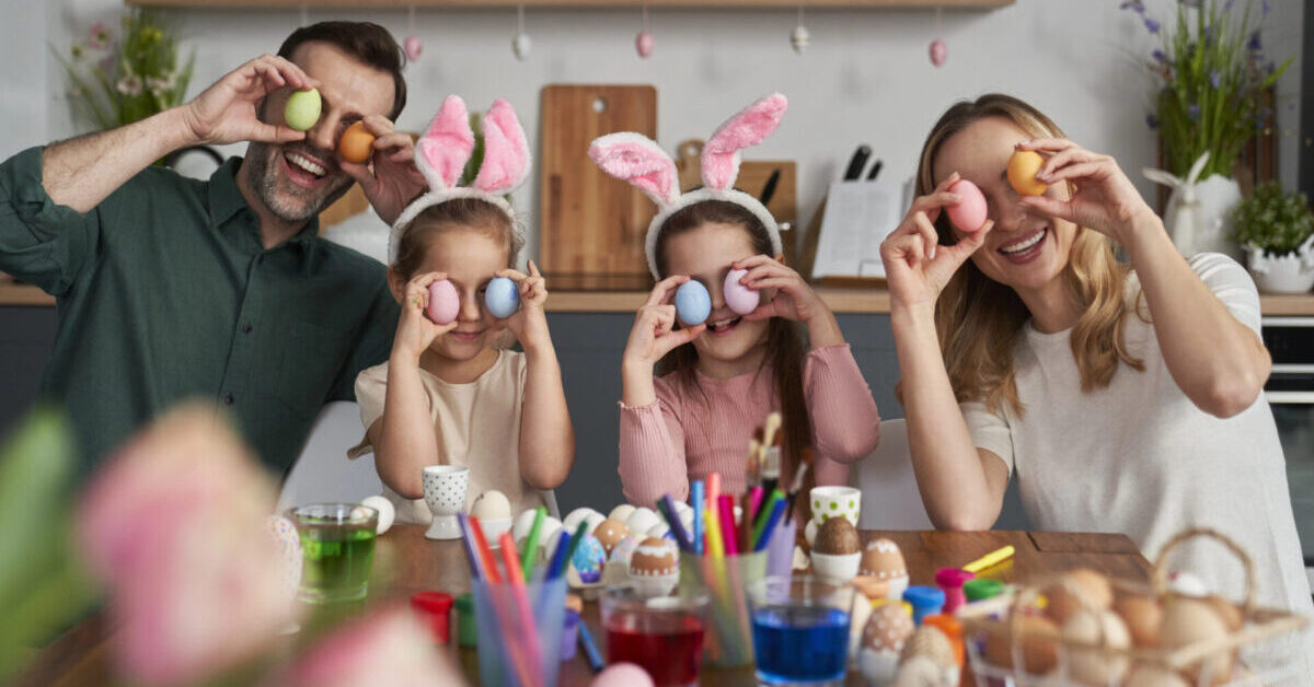 Portrait of playful family covering eyes with easter eggs.