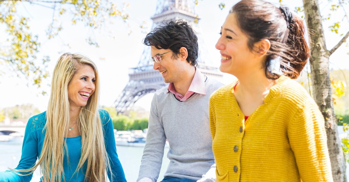 Three joyful friends enjoying time together in a sunny park in Paris by Seine river and Eiffel tower - Friends laughing and spending time outdoors in Paris