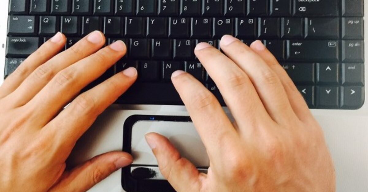 A hand holding a computer keyboard