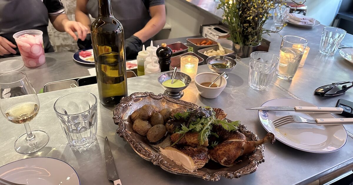Half-chicken with potatoes on silver tray.