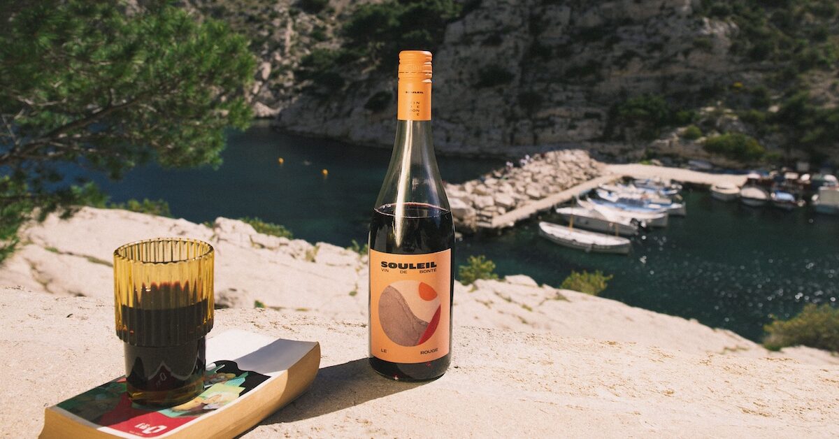 Bottle of red wine against ocean backdrop.