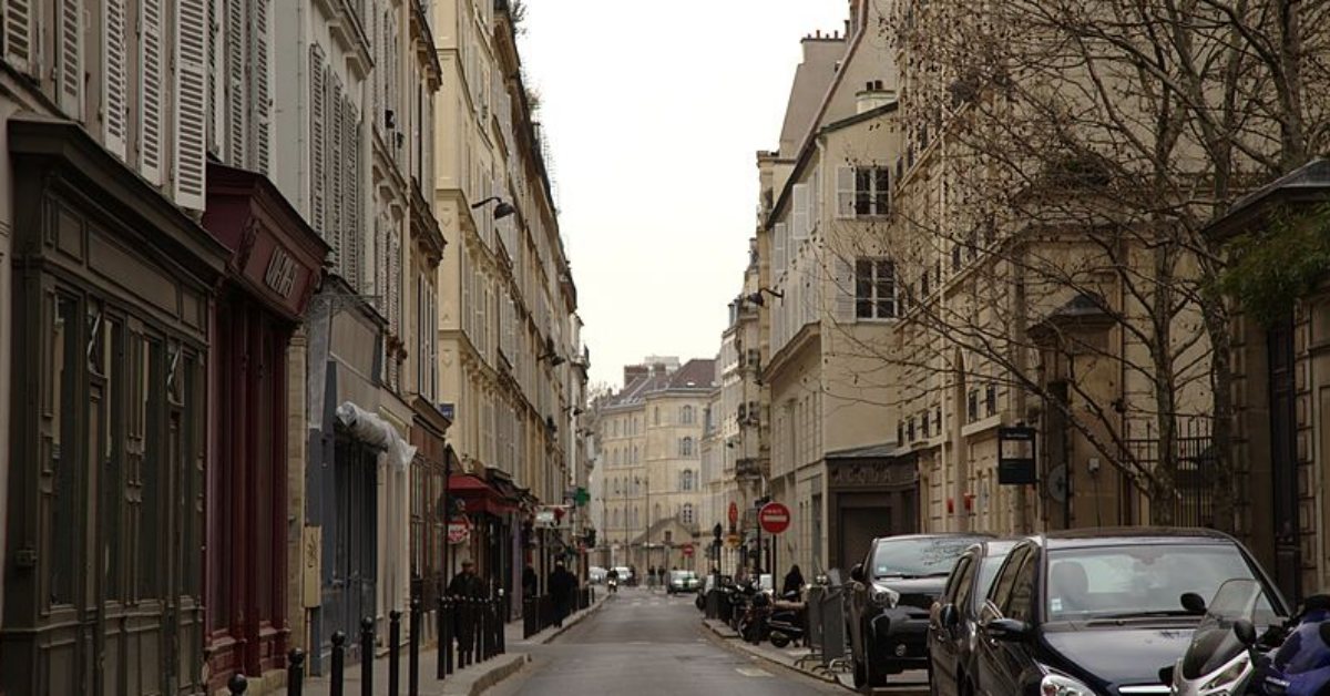 A narrow city street with cars parked on the side of a road