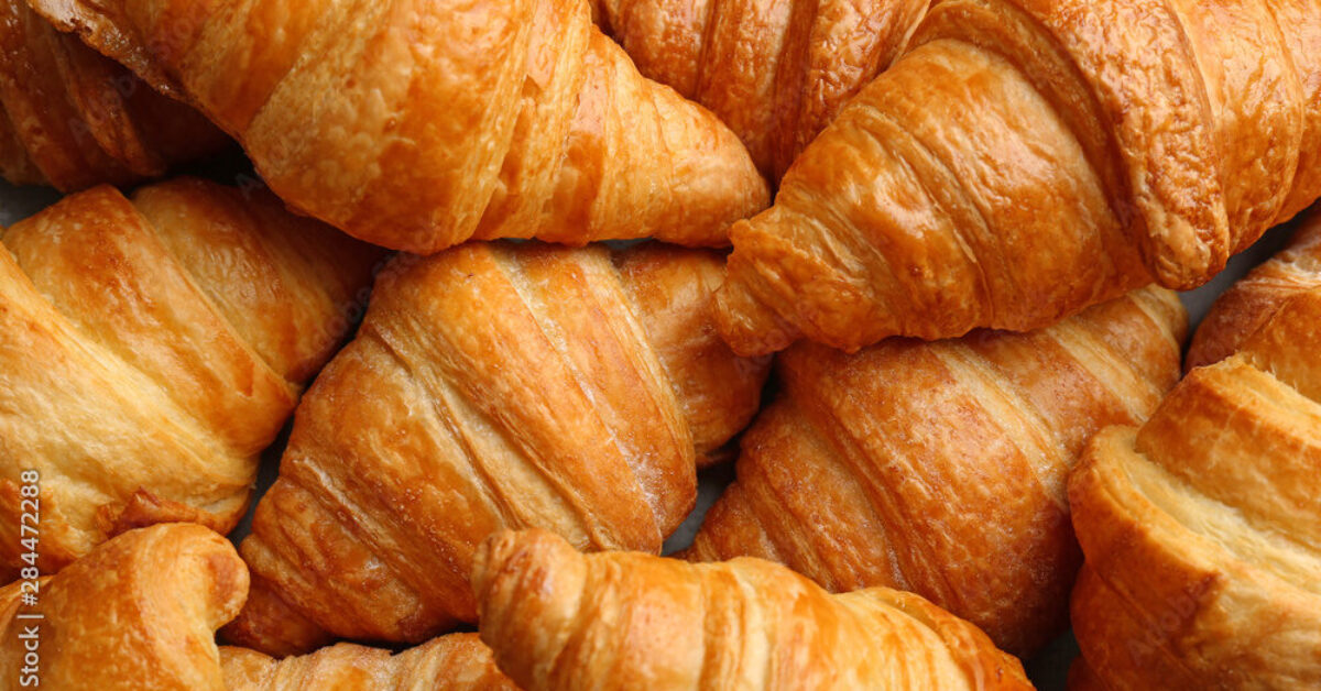 Fresh tasty croissants as background, closeup. French pastry