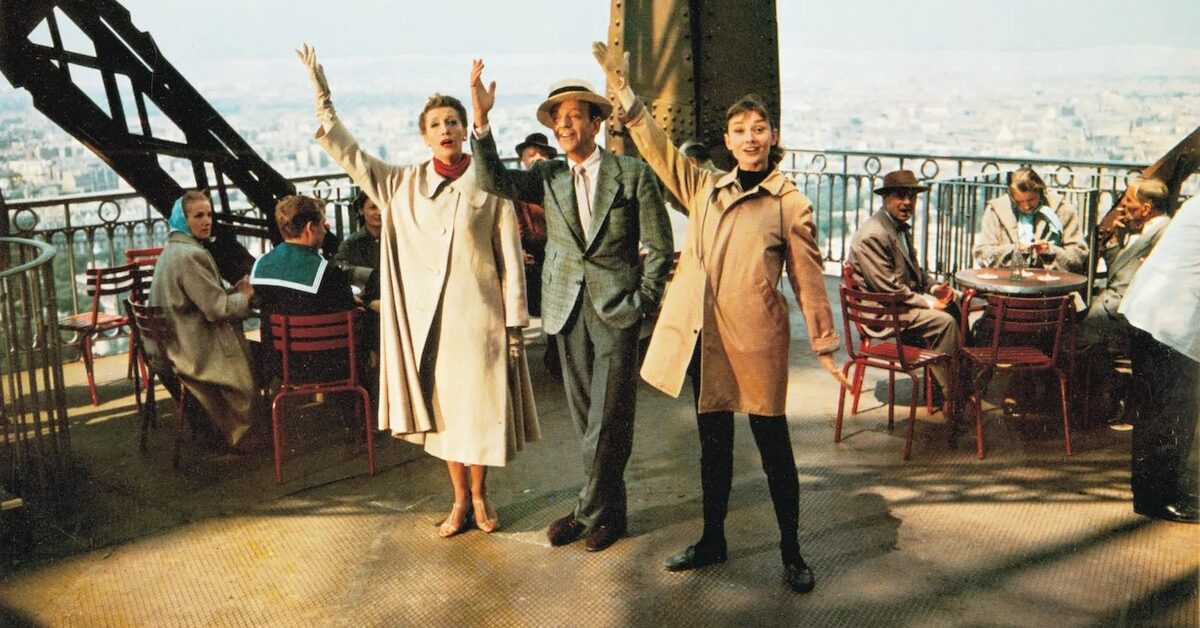 Fred Astaire and Audrey Hepburn waving from the Eiffel Tower platform.