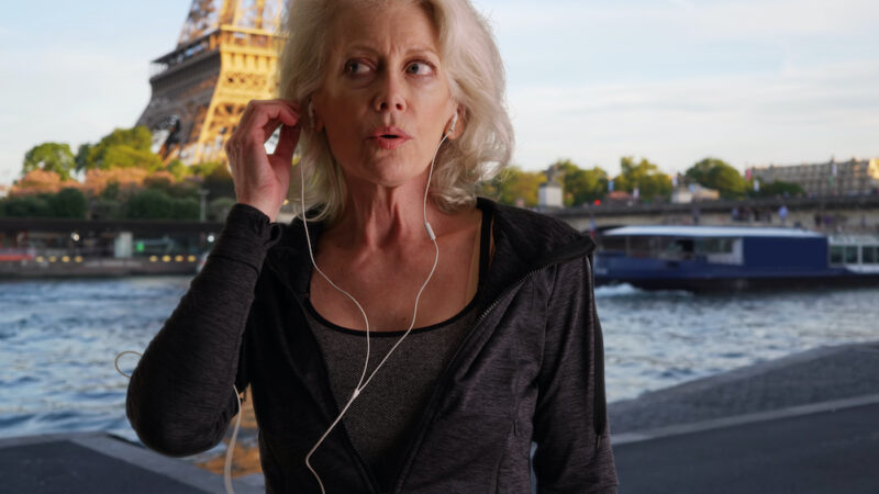 Mature woman jogger by the Seine warming up for run in Paris