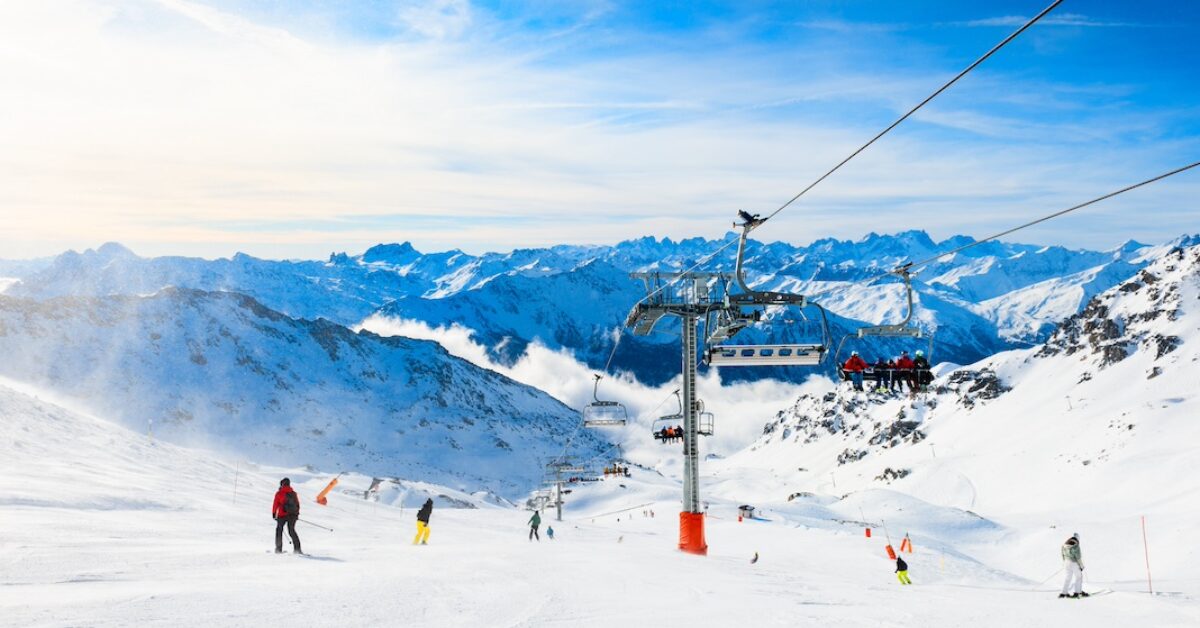 Ski resort in winter Alps. Skiers ride down the slope. Val Thorens, 3 Valleys, France. Beautiful mountains and the blue sky, winter landscape.