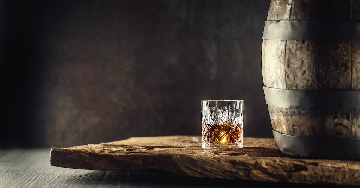 Glass of cognac beside barrel